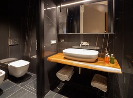 A modern bathroom with a white toilet, a wooden vanity with a sink, and a mirror above the mirror cabinet.