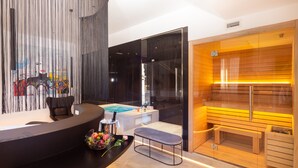 A modern reception area with a black counter, a seating bench, and a sauna visible through a glass partition. - The Corner Duomo Hotel (Milan)