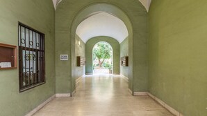 A corridor with green walls, a tiled floor, and an arched ceiling. There are signs on the walls and a window with bars on the left. - Roma Enrico Guesthouse (Rome)