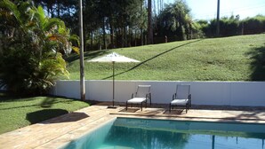 Une piscine avec deux chaises longues et un parasol.