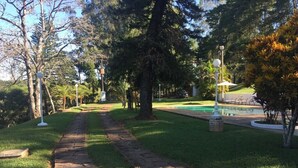 Un chemin pavé mène à un espace piscine entouré d’arbres et d’herbe.