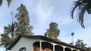Une maison à deux étages avec un balcon, un petit jardin et un ciel dégagé.