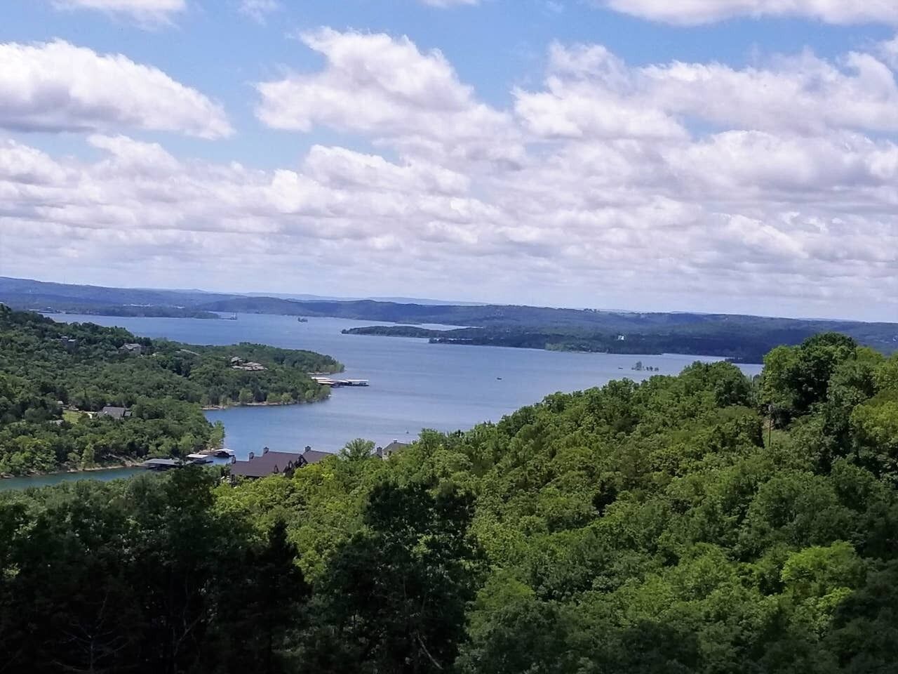 Vista panorámica de un lago rodeado de un bosque denso y colinas.