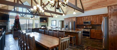A spacious kitchen with wooden cabinets, a large island, and a stone floor.