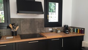 Une cuisine moderne avec des meubles de couleur noire, un plan de travail en bois et une hotte de cuisine noire.