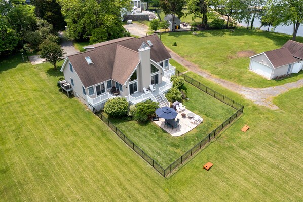 An aerial view of a house with a large deck, a covered patio, and a fenced yard.