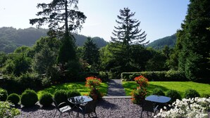 A garden with a gravel path, two tables with chairs, and a variety of plants and flowers. - Tyn Y Fron Country House (Betws-Y-Coed)