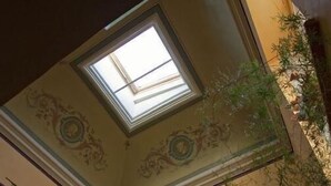 A spiral staircase with a skylight, ornate ceiling, and a wall-mounted light fixture. - La Demeure Du Pareur (Villeneuve-Minervois)