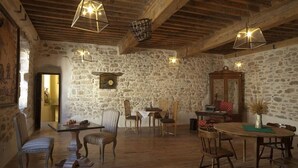A rustic dining room with stone walls, wooden beams, and hanging light fixtures. - La Demeure Du Pareur (Villeneuve-Minervois)