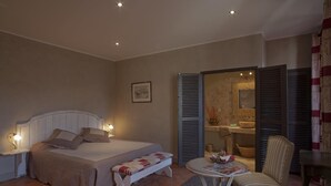 A bedroom with a bed, bedside tables, a chair, and a small table with a magazine. - La Demeure Du Pareur (Villeneuve-Minervois)