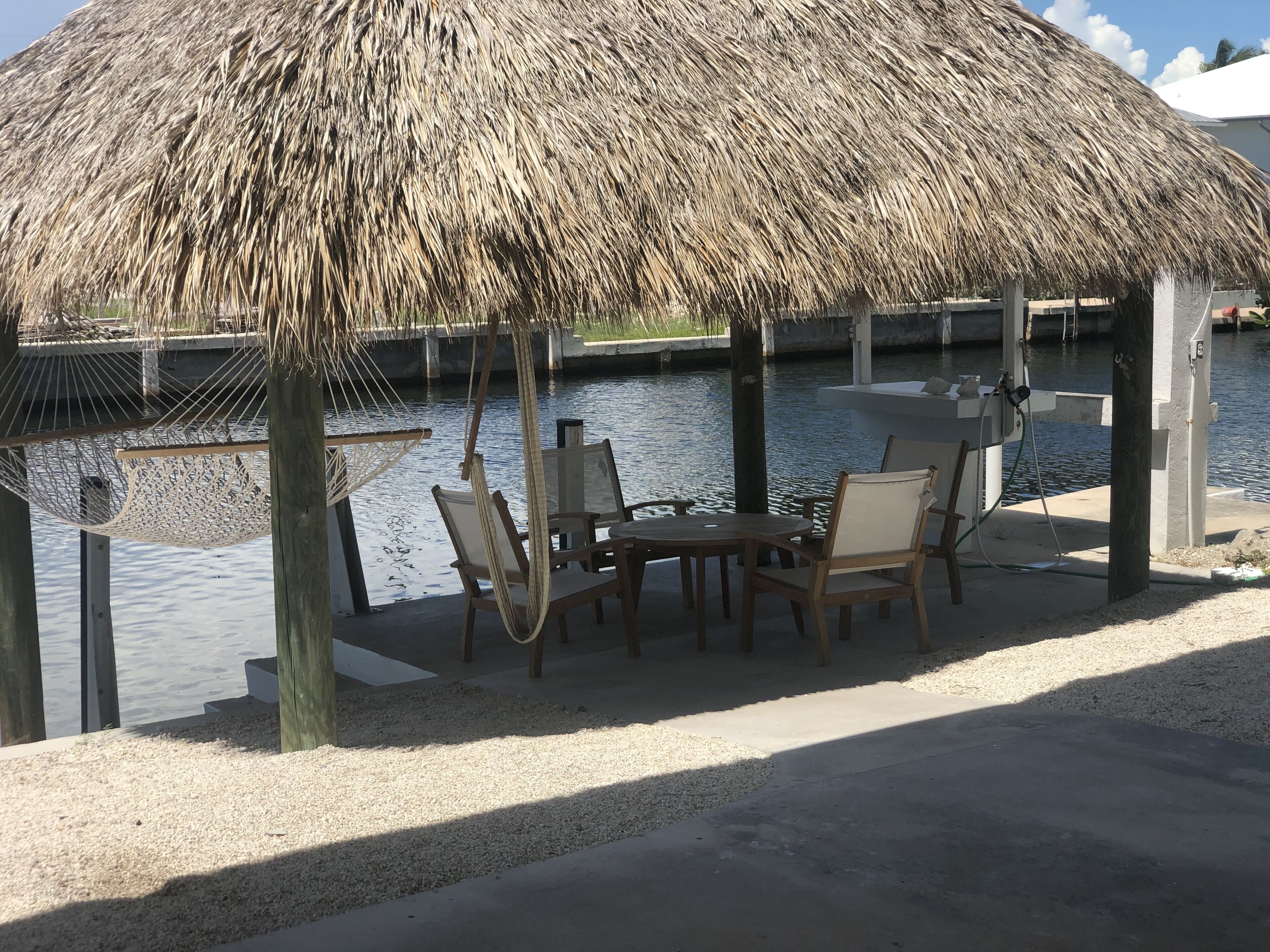 Een terras met rieten dak, tafels en stoelen aan het water.