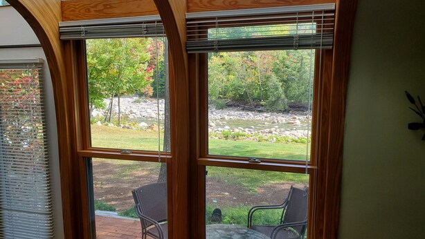 Ein Zimmer mit großem Fenster und Blick auf einen Garten mit Tisch und Stühlen.