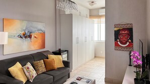 A modern living room with a grey sofa, a coffee table, and artwork on the wall.