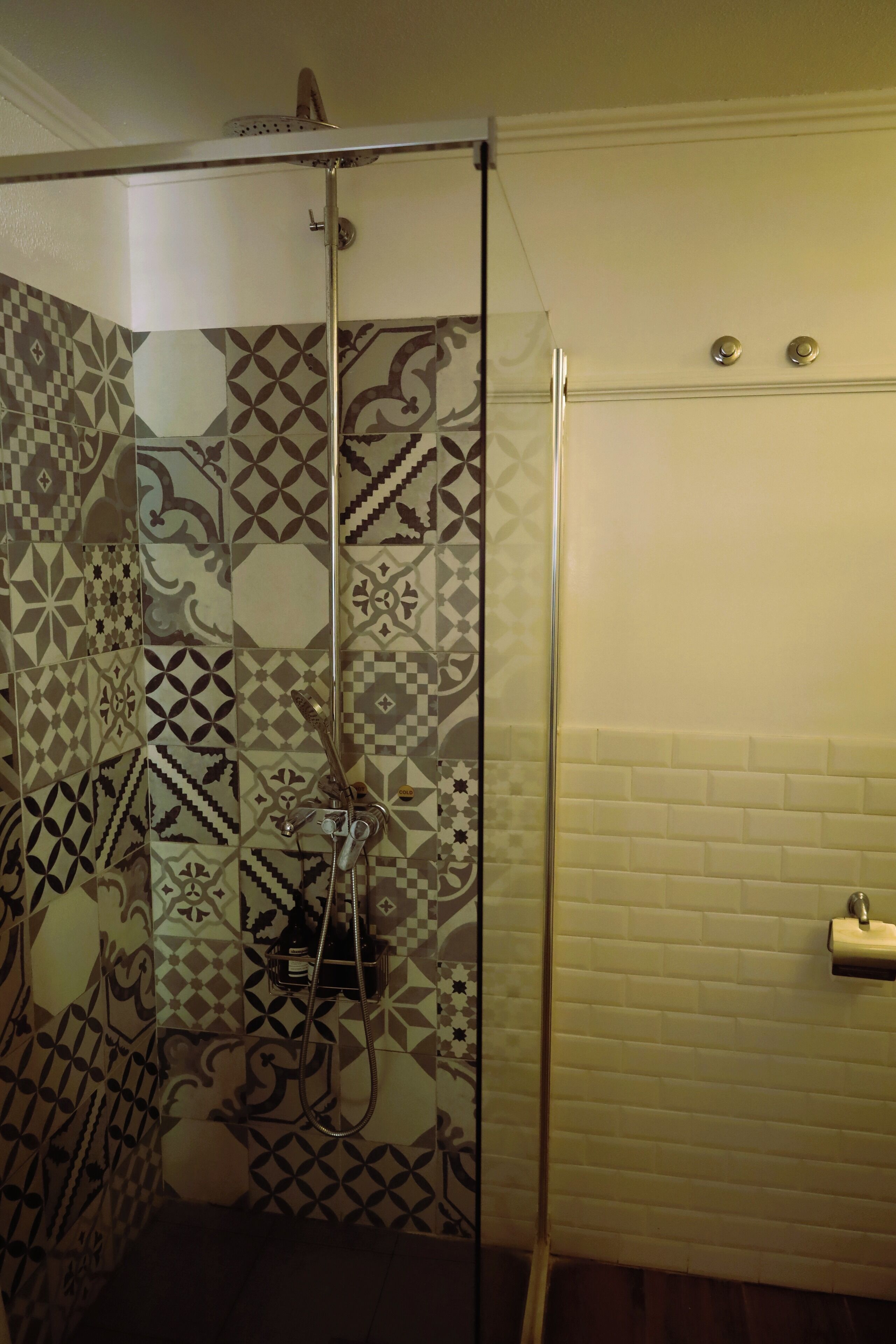 Um chuveiro com azulejos estampados e porta de vidro.