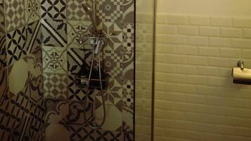 Um chuveiro com azulejos estampados e porta de vidro.