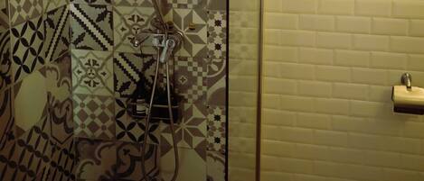 A shower with patterned tiles and a glass door.