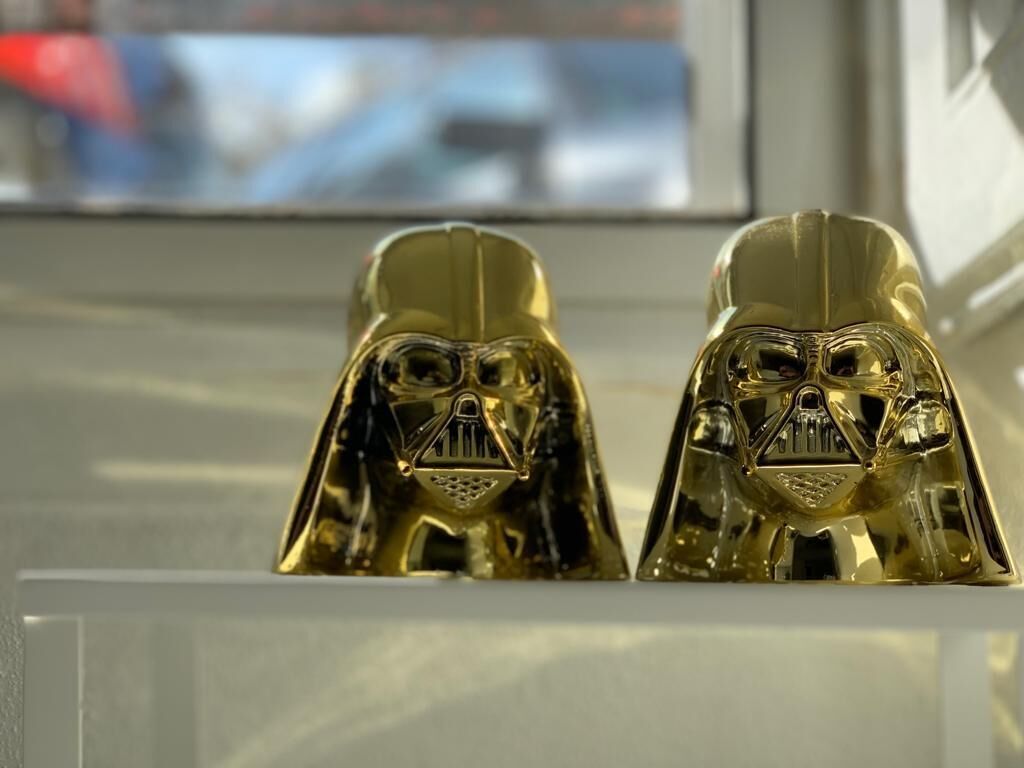 Deux figurines dorées de Dark Vador, posées sur une étagère blanche.
