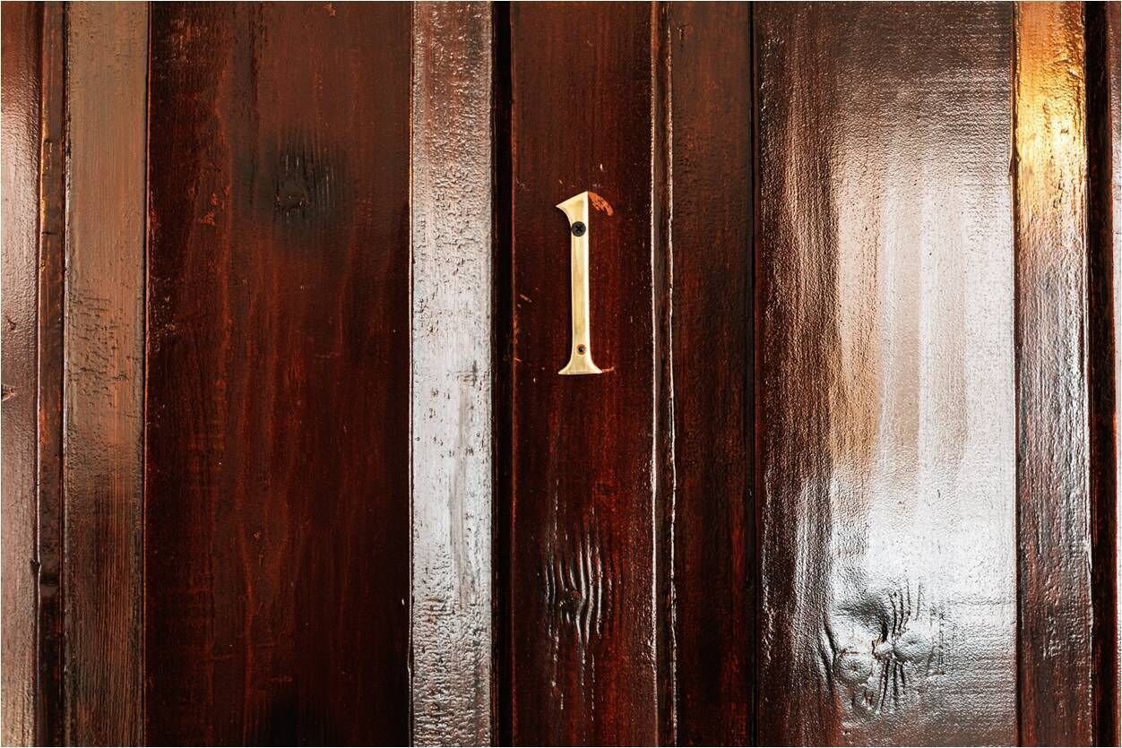 A wooden door with a brass number '1' handle.