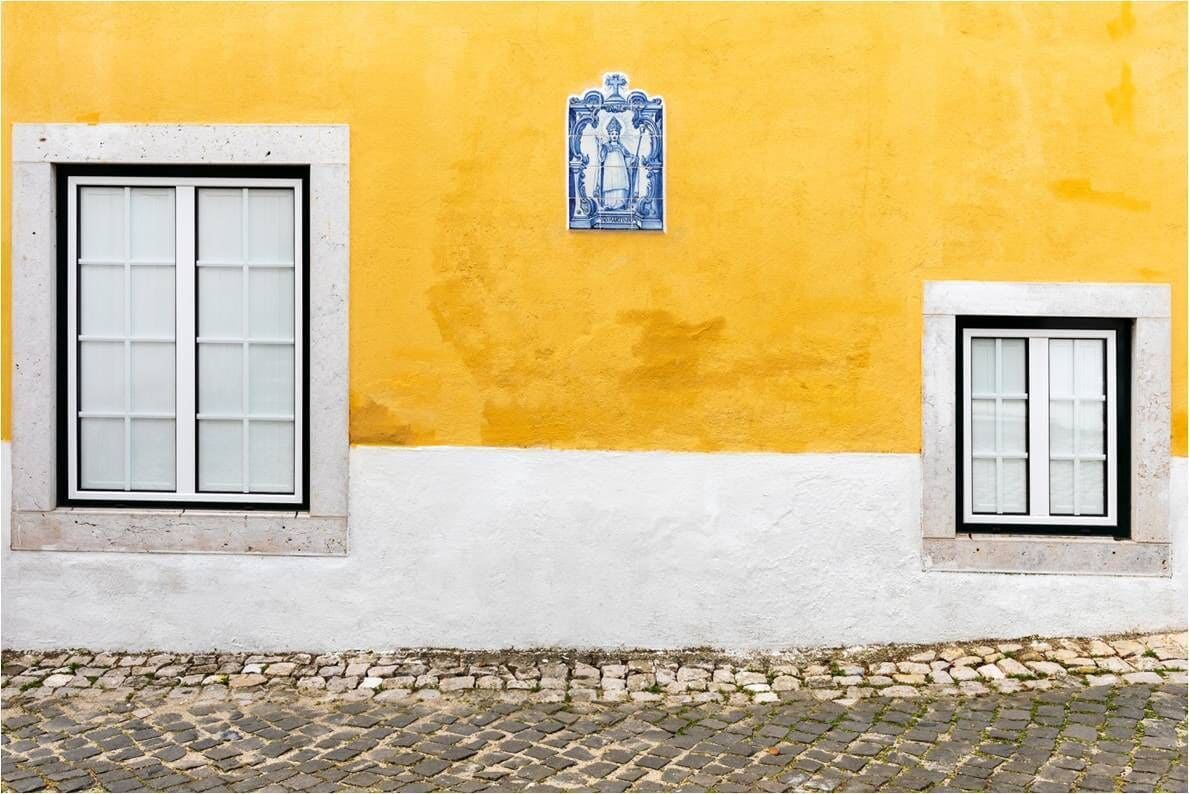 A building with two windows and a decorative tile above the right window.