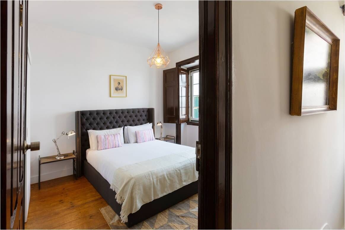 Un dormitorio con una cama grande, una mesita de noche, una lámpara, un aplique colgante y un cuadro en la pared.