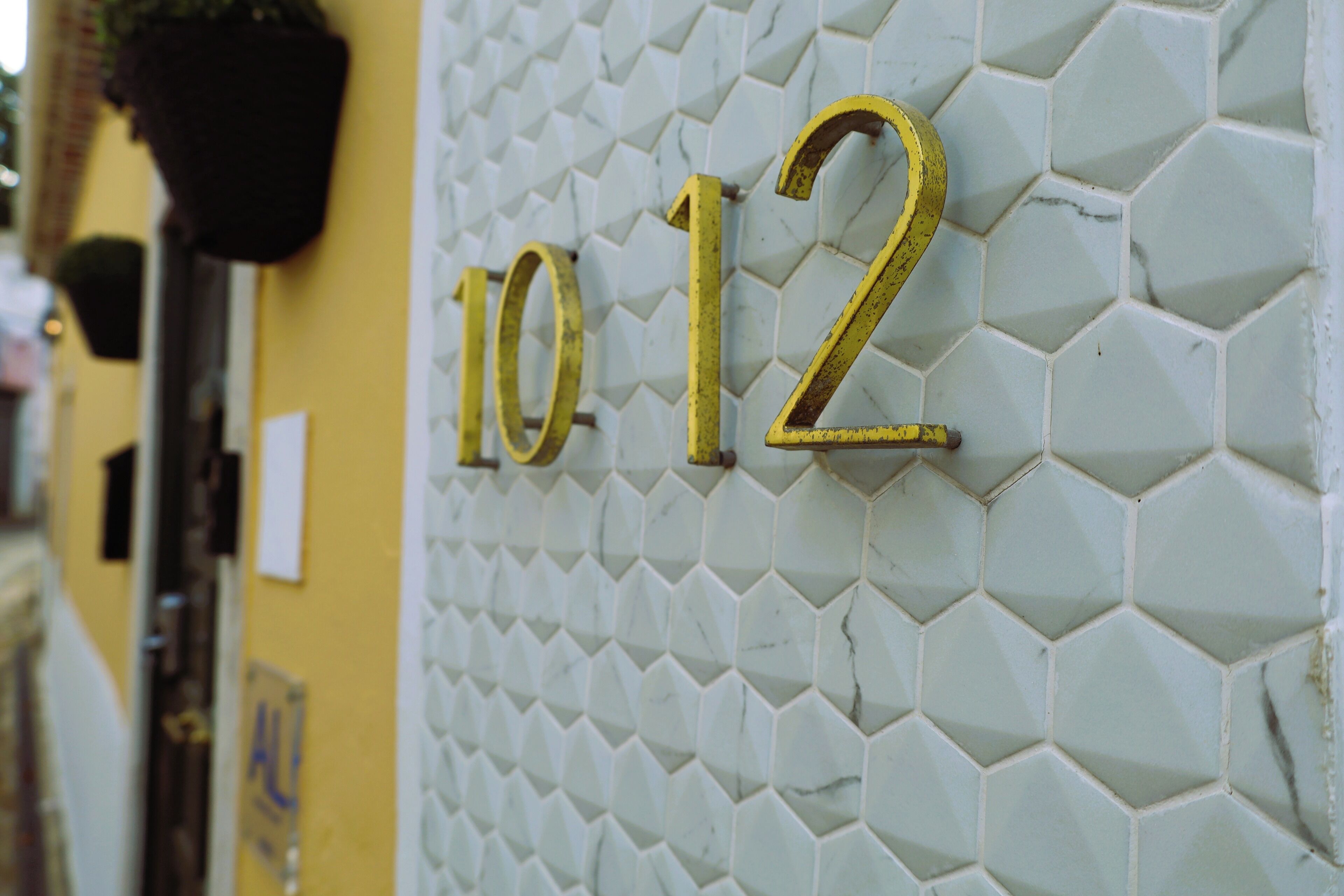Paret amb un dibuix d'hexàgons i els números "10 12" daurats.