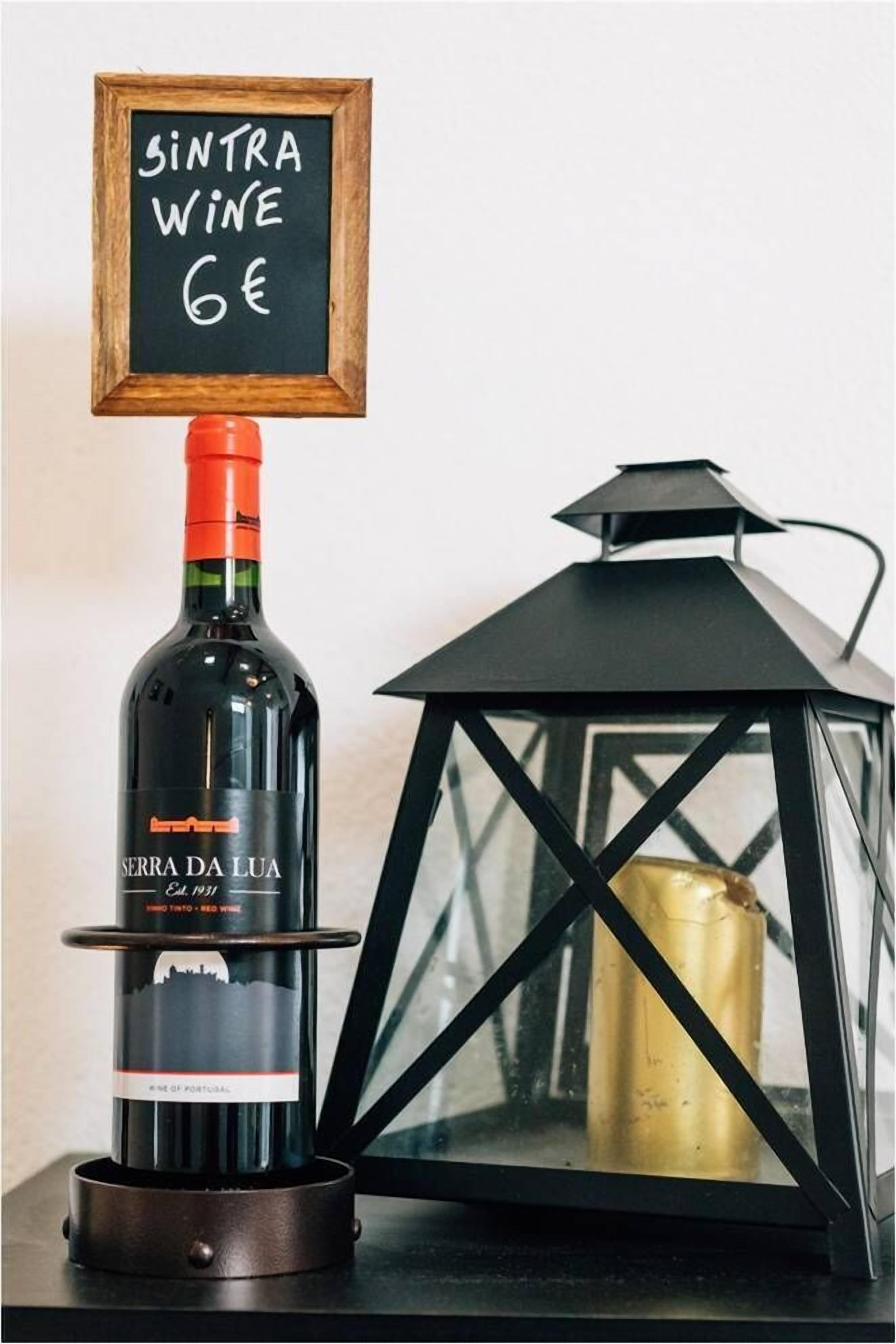 Una botella de vino Serra da Lua con un cartel de precio encima, colocada al lado de un farol negro.