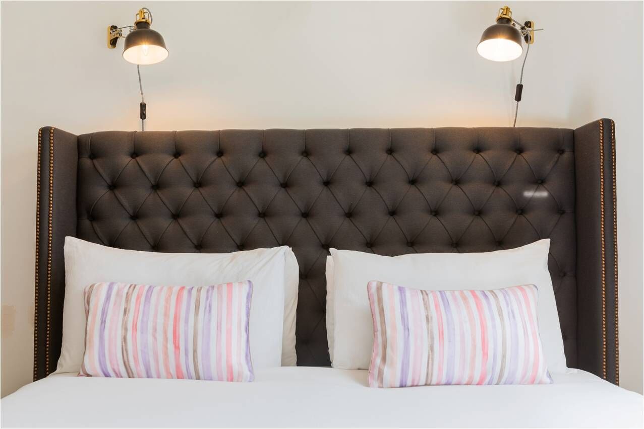 A bed with a tufted headboard, two bedside lamps, and striped pillows.