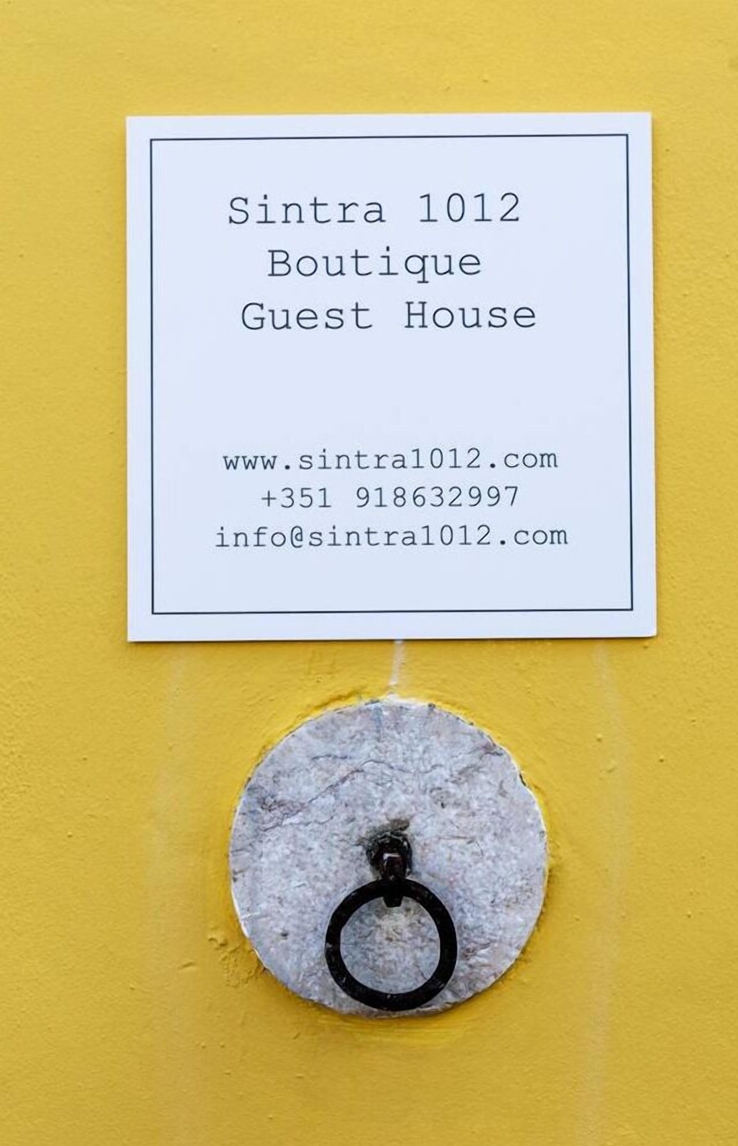 A sign for Sintra 1012 Boutique Guest House with contact information.