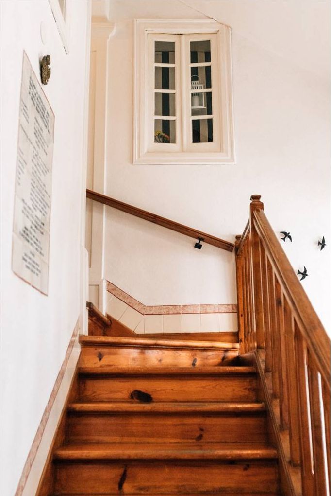A wooden staircase with a white wall and a window above it.