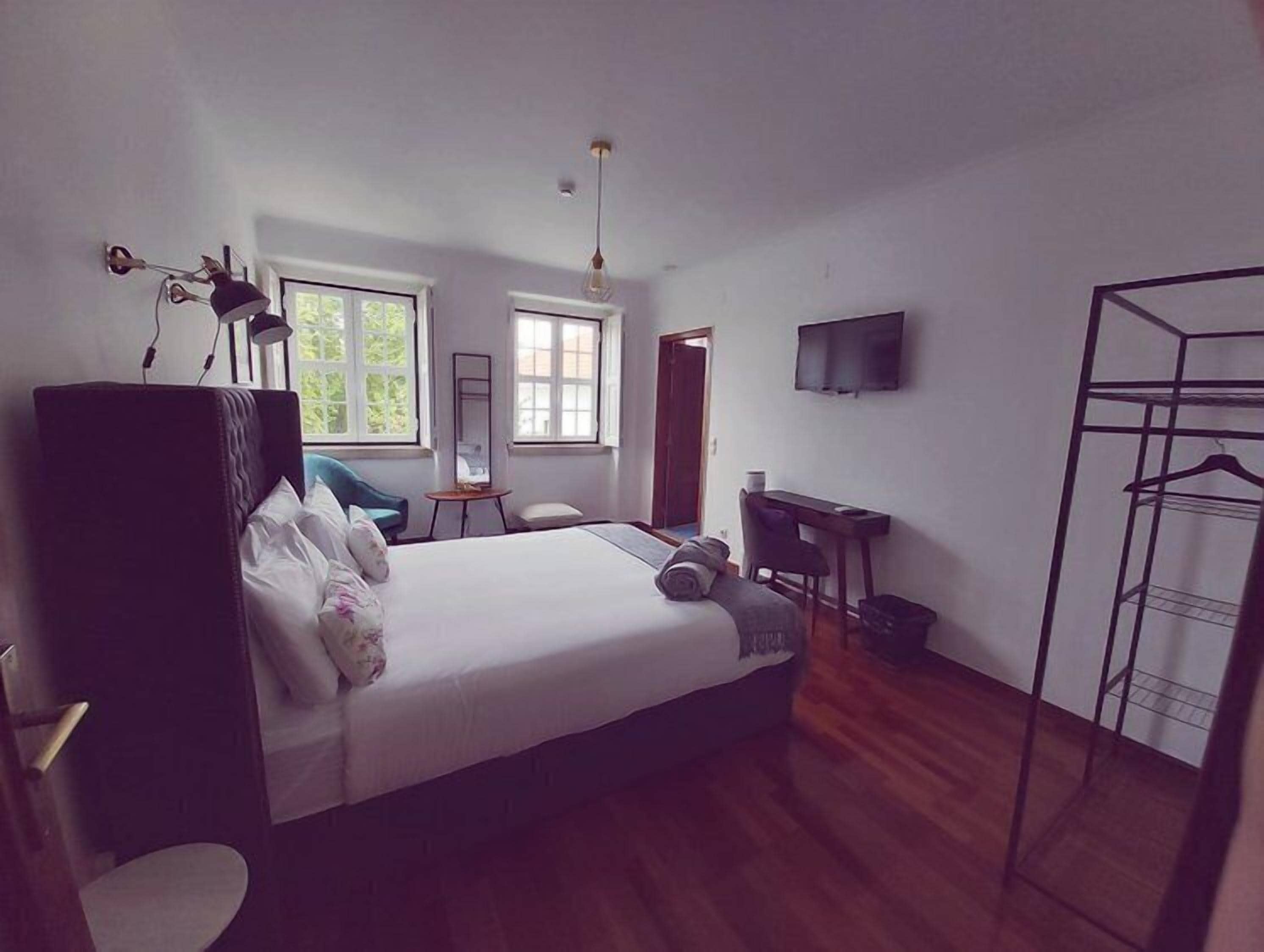 Een slaapkamer met een bed, een bureau, een televisie en een kledingkast.