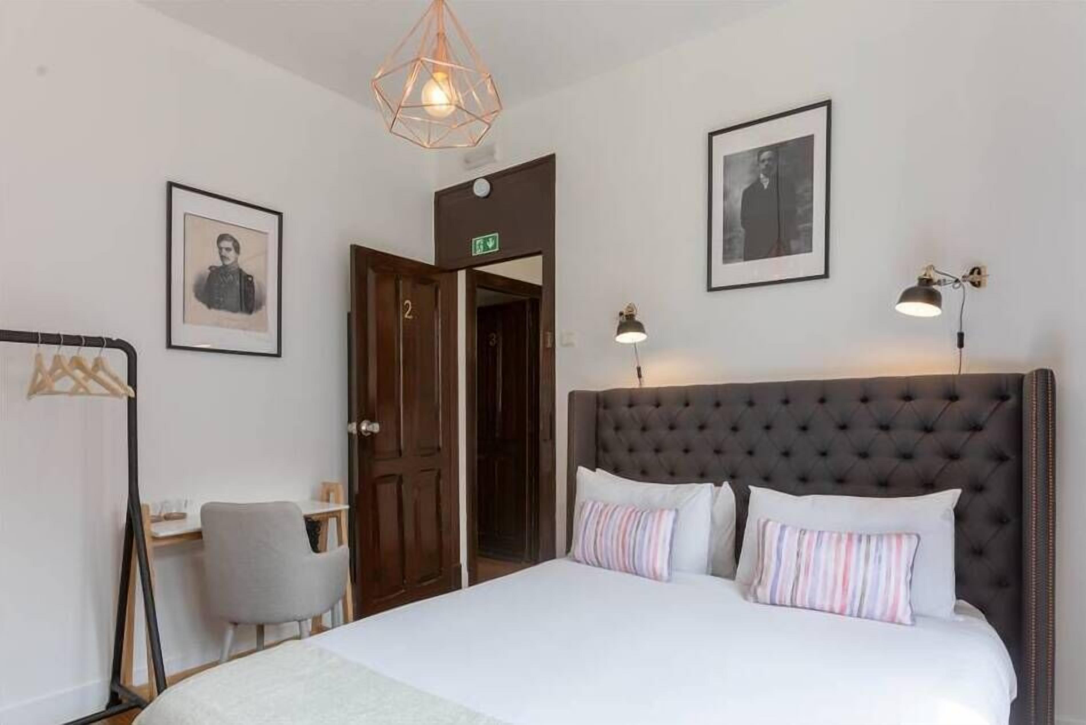 Une chambre à coucher avec un grand lit, un bureau, une chaise et deux tableaux encadrés accrochés au mur.