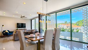 A modern living room with a dining area, large windows, and a ceiling fan. - Chic, Spacious Condo | Great Walkability, Pool, Gym, Rooftop Views (Puerto Vallarta)