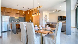 A modern kitchen with wooden cabinets, a central island, and a dining area with a wooden table and chairs. - Chic, Spacious Condo | Great Walkability, Pool, Gym, Rooftop Views (Puerto Vallarta)
