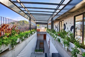 A modern architectural space with a glass ceiling, concrete walls, and a central staircase.