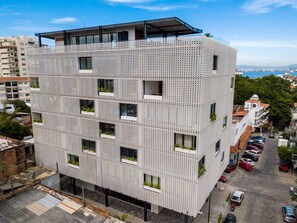 A modern building with a unique perforated facade, multiple balconies, and a rooftop terrace. - Chic, Spacious Condo | Great Walkability, Pool, Gym, Rooftop Views (Puerto Vallarta)