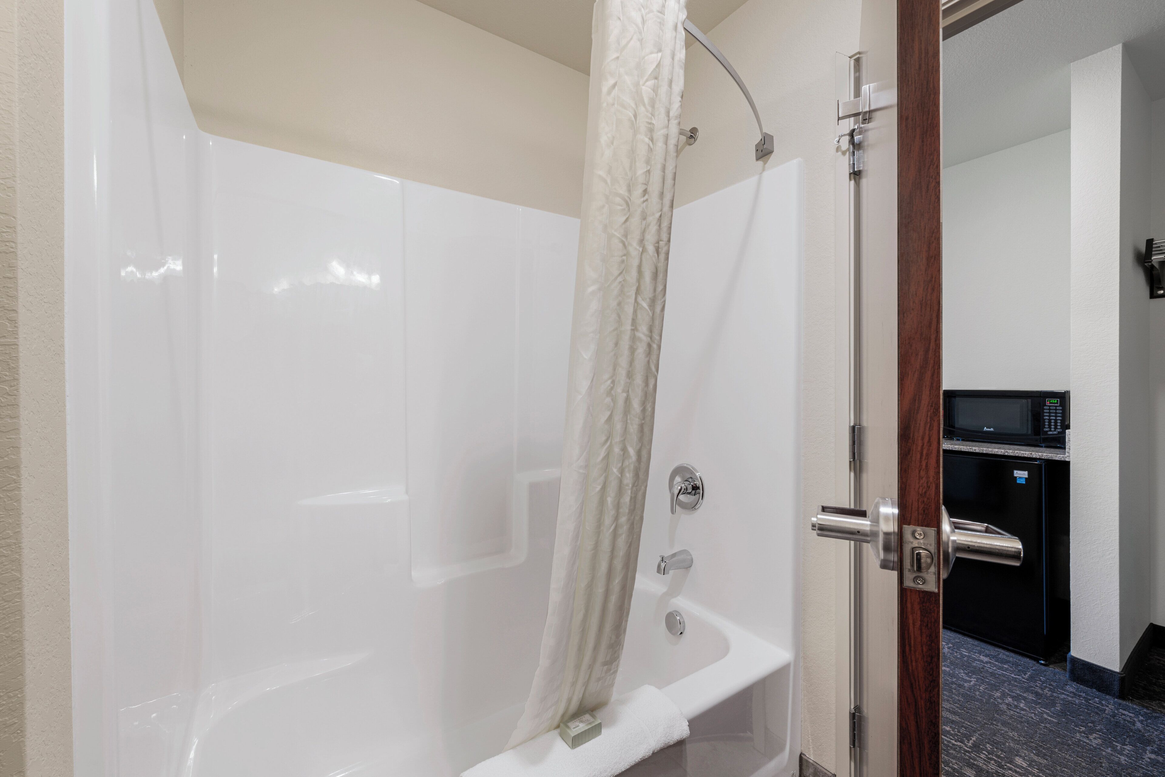 Un baño moderno con cabina de ducha de vidrio, una bañera blanca y un microondas empotrado.