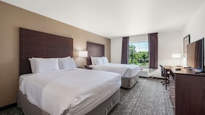Une chambre d’hôtel avec deux lits, un bureau et une télévision.