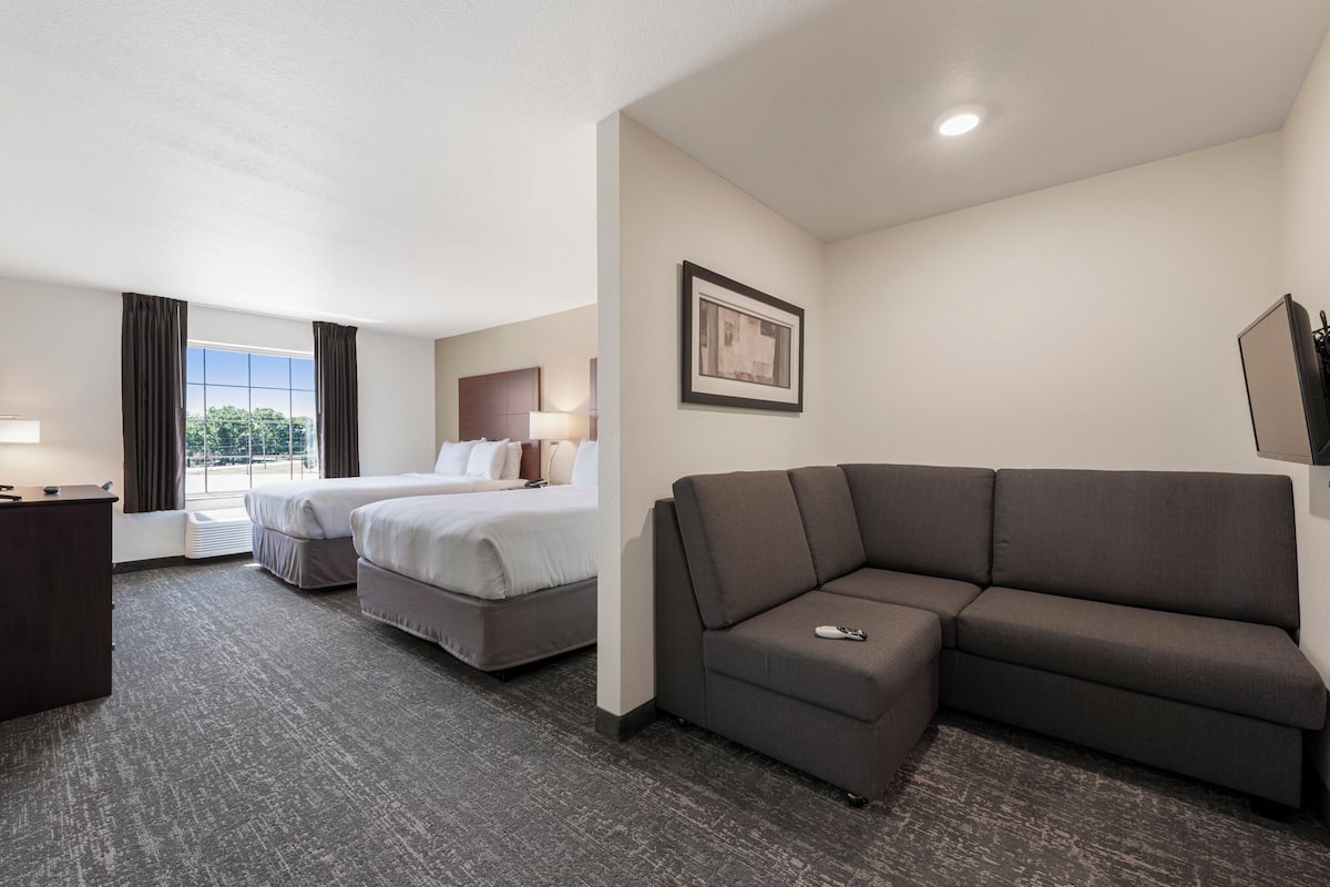 Une chambre d’hôtel avec un grand lit, un canapé, un bureau et une fenêtre avec des rideaux.