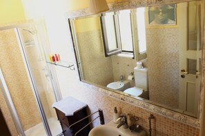 Une salle de bain avec une douche à parois de verre, un lavabo, des toilettes et un miroir doté d’un cadre décoratif.