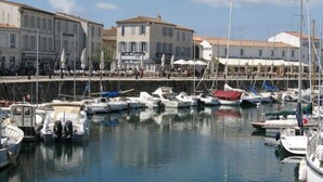 A marina with several boats docked, buildings in the background, and a clear sky. - Lavender Lodge, sleeps up to 6 people, (Étaules)