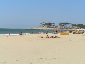 A sandy beach with people sunbathing and swimming. There are trees and a rocky outcrop in the background. - Lavender Lodge, sleeps up to 6 people, (Étaules)