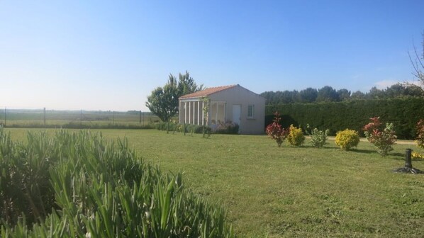 A single-story building with a red-tiled roof, surrounded by a well-maintained lawn and various shrubs. - Lavender View is a cosy cottage for 2 with far reaching views (Étaules, Nouvelle-Aquitaine)