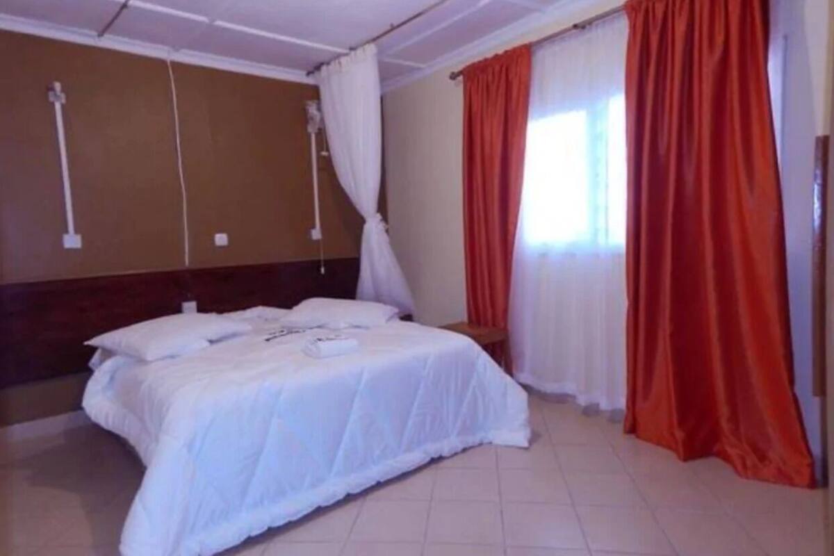 Une chambre d’hôtel avec un lit, des rideaux et une fenêtre.