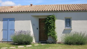 Una casa con techo de tejas, puerta de madera y un cerrojo azul.