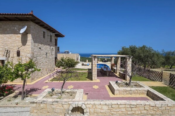 A stone building with a pool and outdoor seating area, overlooking a body of water. - Grecian Villas Chania (Platanias)