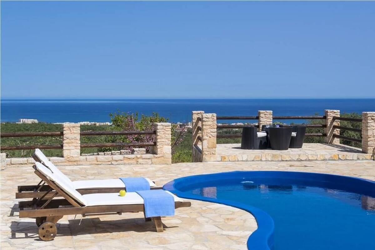 Una piscina con sillas de descanso y una terraza de piedra, con vista a un cuerpo de agua.