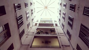A multi-level building with a central atrium, multiple balconies, and a large skylight. - Miracolo Al Duomo (Naples)