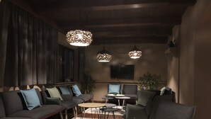 Un rincón de sala acogedor con sofás, mesas redondas e iluminación colgante.