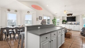 A kitchen with a large island, white cabinets, and a ceiling fan.