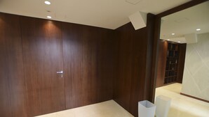 A modern bathroom with dark wood paneling, a large mirror, and a tiled floor. - Rondone Bianco 5-7 (Como)